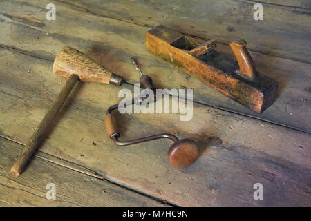 Mazo antiguo, manual taladro de mano y mano de plano en el suelo de madera de la habitación vacía dentro de una vieja casa estilo cabaña de 1800. Foto de stock
