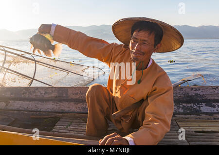 Pierna remo pescador Intha celebración de pescado en el Lago Inle, el Estado de Shan, Myanmar (Birmania), Asia en Febrero - fisherman celebración pescado