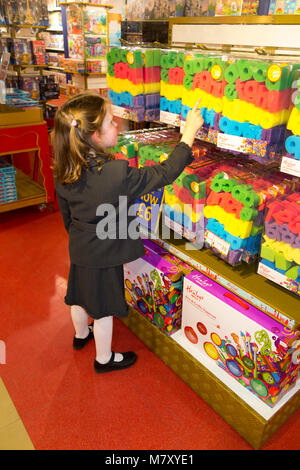 Niña de 6 años años seis años / niño / Niños / Niños / niño mirando y probando los juguetes en una tienda de juguetes de Londres. Regent Street, Londres, Reino Unido.