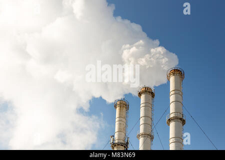 Fumar en pipa haciendo nubes contra el cielo azul de fondo. La contaminación del aire de dióxido. Contaminación ambiental Foto de stock