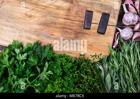 Las hierbas frescas y especias en placa de corte sobre mesa de madera antigua. Comida sana y concepto de cocina abierta. Hierbas de jardinería. Vista superior Foto de stock