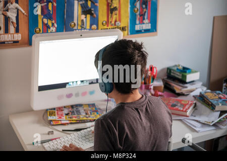 Surrey, UK,10 años boy en computadora en su dormitorio, vista posterior