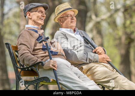 Los ancianos relajante en un banco al aire libre Foto de stock