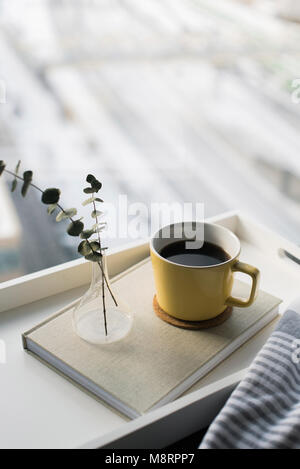 Un alto ángulo de visualización de las ramitas en un jarrón de diario por taza de café contra la luna Foto de stock