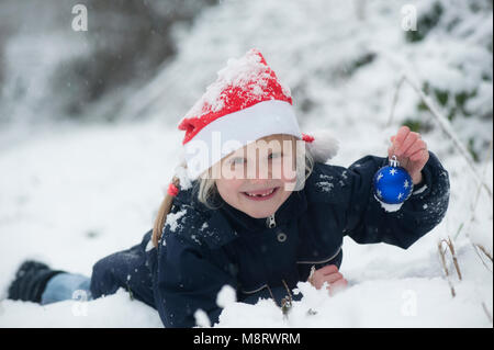 Ein Madchen Mit Weihnachtsmutze Und Kugel Im Schnee Fotografia De Stock Alamy