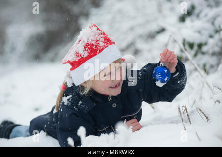 Ein Madchen Mit Weihnachtsmutze Und Kugel Im Schnee Fotografia De Stock Alamy