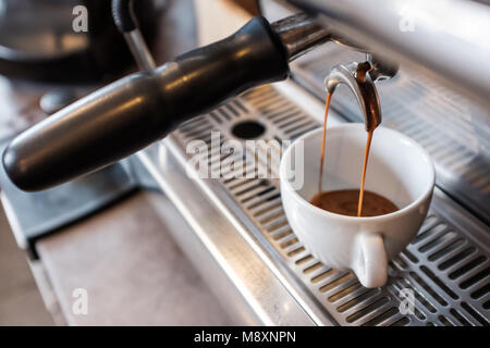Espresso dulce goteando por portafilter de máquina de café en la taza blanca Foto de stock