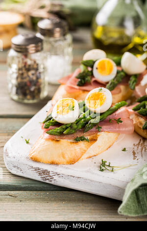 Sandwichera fresco con jamón, espárragos y huevos de codorniz Foto de stock