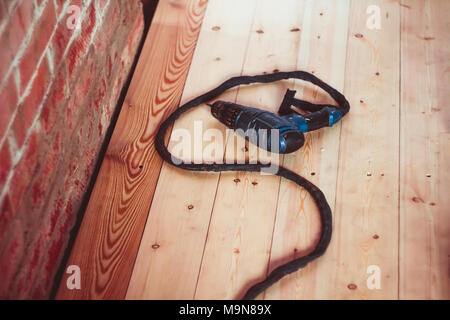 Cortador eléctrico y taladrar azulejos acostado sobre el terreno entre el aserrín Foto de stock