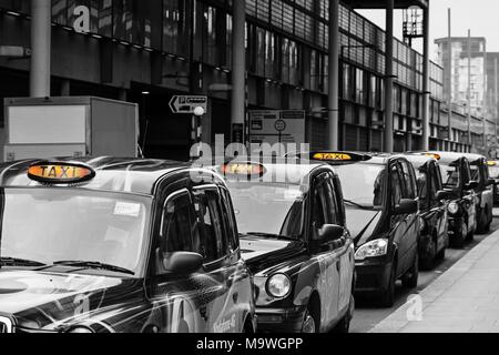 La cola de los taxis negros de Londres en una fila en una parada de taxis esperando para recoger pasajeros, cerca de la estación de Kings Cross para alquilar con luz encendida