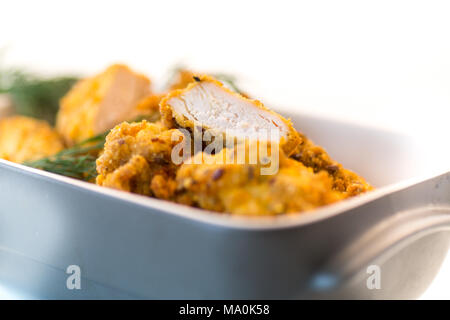 Pollo frito rebozado con eneldo en forma de cerámica sobre un fondo blanco. Foto de stock