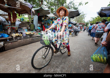 Mujer de mediana edad en bicicleta alrededor de Chhlong mercado, la Provincia de Kratie, Camboya, Sudeste asiático
