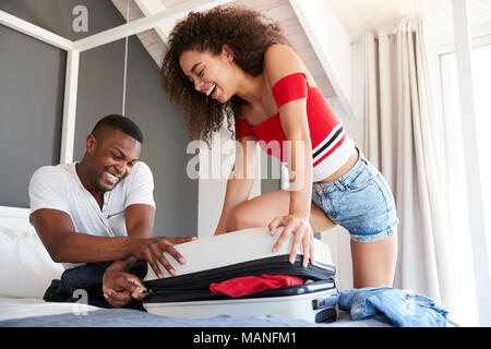 Par intentando cerrar la maleta de vacaciones completo en dormitorio