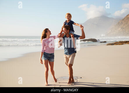 Hijo de padres llevando a hombros en vacaciones en la playa