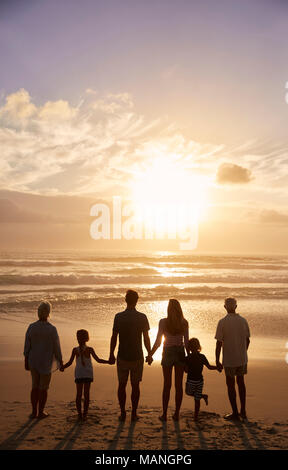 Vista trasera de generación múltiple familia silueteado en la playa