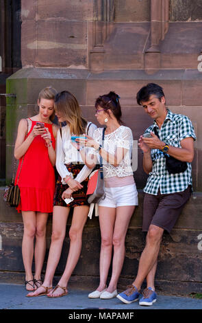 Dos mujeres jóvenes, de mediana edad hombre y mujer mirando sus teléfonos celulares, Estrasburgo, Alsacia, Francia, Europa, Foto de stock