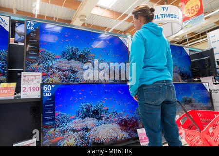 Mujer mirando su nuevo televisor de alta definición 4k pantallas en almacén eléctrico