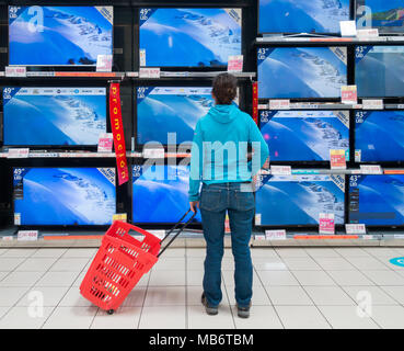 Mujer mirando nuevas pantallas de TV de alta definición en almacén eléctrico