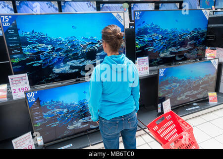 Mujer mirando su nuevo televisor de alta definición 4k pantallas en almacén eléctrico