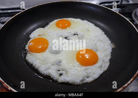 Freír tres huevos en sartén antiadherente Foto de stock