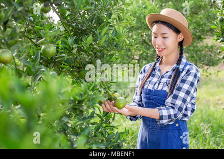 El agricultor joven chica sujetando los árboles de naranja en las manos.