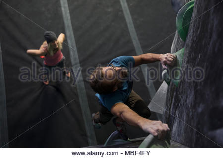 Decididos, centrado macho maduro escalador muro de escalada en el gimnasio de escalada