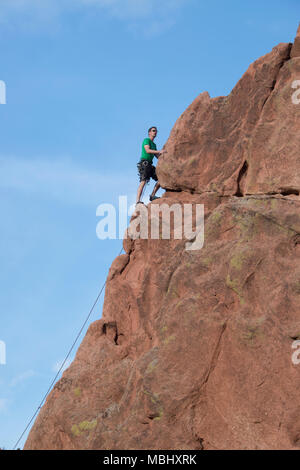 Escalador hombre subiendo los acantilados de arenisca en el Jardín de los dioses, el 4 de abril, 2016