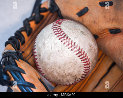 Imagen de fondo deportivo cerca de un antiguo utilizado piel gastada de béisbol con cordones rojos dentro de un guante de béisbol o mitt mostrando intrincados detalles Foto de stock