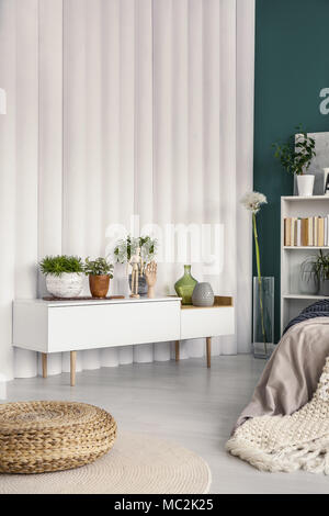 Pouf casi blanco armario con plantas en el dormitorio moderno interior con pared de tubo Foto de stock
