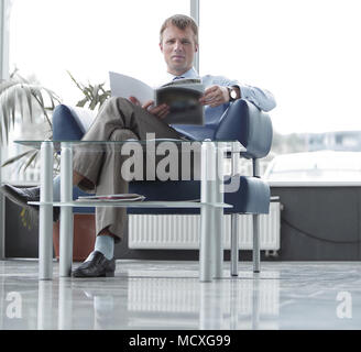Empresario Leer revista en la sala de espera. Foto de stock