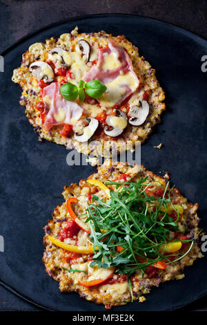 Pizza de coliflor guarnecida con rúcula y pimiento y champignons y jamón cocido Foto de stock