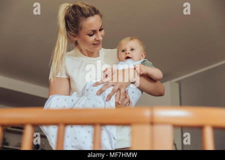Poner madre bebé en su cuna para dormir Foto de stock