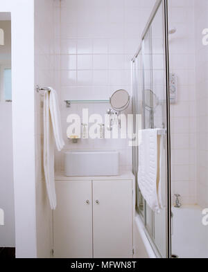 Lavabo cuadrado sobre unidad de armario en baño de azulejo blanco Foto de stock