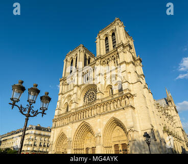 La fachada y campanarios de la catedral Notre-Dame de París, mostrando los tres portales y el rosetón de una vendimia la calle la luz en el primer plano. Foto de stock