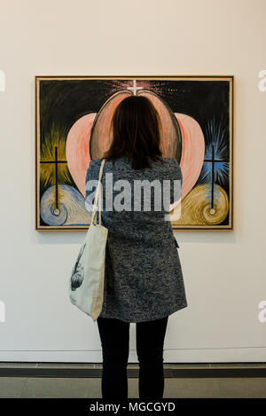 Mujer mirando la pintura en la pared, su cabello alineado con la obra de arte, como si la parte de la ilustración, vista trasera, Londres, Inglaterra