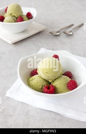Recipientes con dos cucharadas de matcha helado casero y frambuesas frescas. Foto de stock