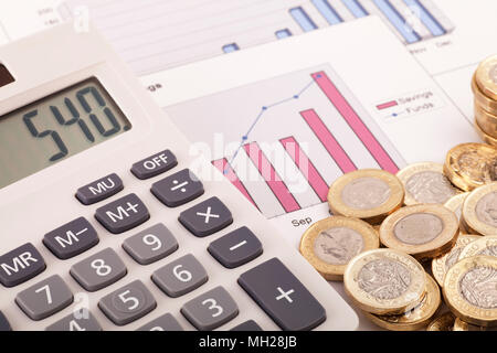 Una calculadora sentado en algunos gráficos etiquetados ahorros y fondos con algunas nuevas (post 2016) pound monedas. Foto de stock
