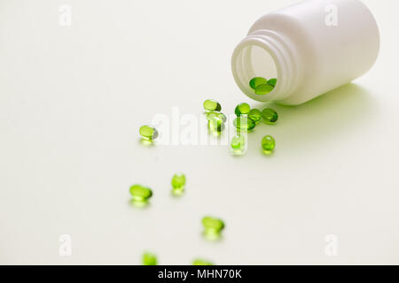 Las cápsulas verdes sobre una cucharadita aislado sobre fondo blanco. Foto de stock