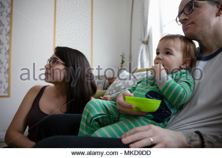 Joven familia comiendo, viendo la televisión