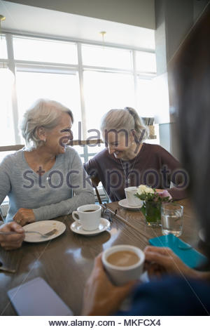 Riendo, altos funcionarios de la mujer bebiendo café en el café Riendo, altos funcionarios de la mujer bebiendo café en el café