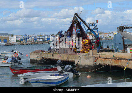 La tripulación de un cerquero recopila sus redes en el puerto pesquero de Olhão, Algarve, Sur de Portugal Foto de stock