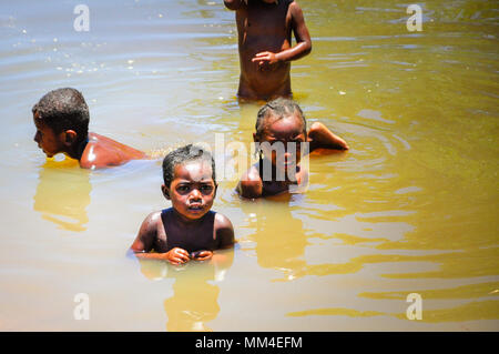 Algunos desconocidos que los niños juegan en un estanque de agua sucia. Madagascar es uno de los países más pobres de la tierra Foto de stock