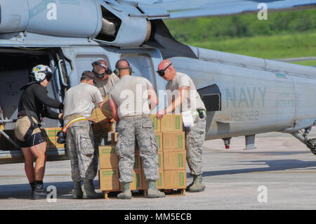 Los miembros de la 164ª Escuadrilla de preparación logística, Tennessee, de la Guardia Nacional Aérea y Marina de los EE.UU. Oficial de 2ª clase mezquina guerra de aviación de carga, Especialista de la Agencia Federal de Manejo de Emergencias de raciones de emergencia a un UH-60L Black Hawk a un helicóptero cerca de la terminal aérea del aeropuerto de Santa Cruz, el próximo 9 de septiembre. En un esfuerzo conjunto, soldados, aviadores y los miembros de la marina trasladó personal y enormes cantidades de carga desde Santa Cruz a Santo Tomás y San Juan para facilitar la recuperación del huracán Irma socorro. Foto de stock