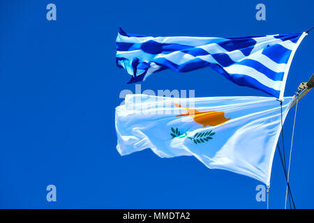 Ondeando banderas griegas y Cipriano agaist el cielo azul en el viento fuerte con espacio para texto Foto de stock