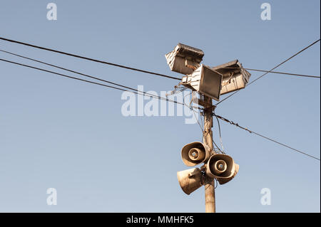 Casco exterior público altavoces, megáfonos y reflectores en poste de metal negro con cables eléctricos Foto de stock