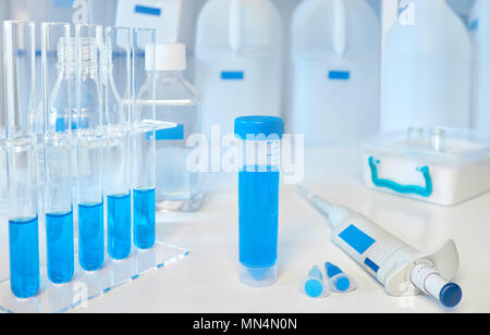 Antecedentes científicos en azul y blanco. Las muestras líquidas en tubos de vidrio y plástico, pipeta automática y cesta de hielo. Foto de stock