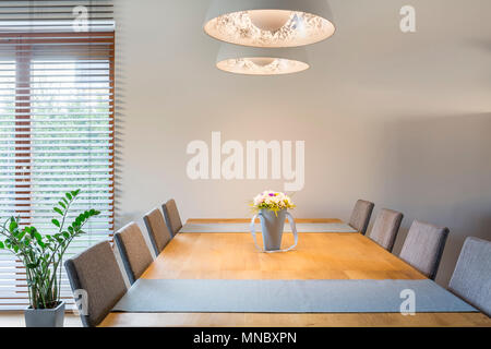 Interior de madera con mesa de comedor, sillas y lámpara colgante Foto de stock
