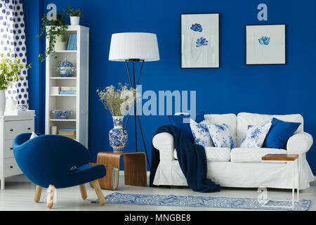 Sillón blanco en el salón azul con accesorios de porcelana Foto de stock