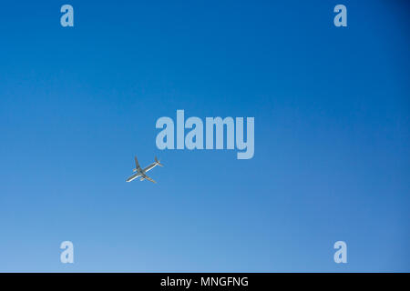 Avión de pasajeros vuela sobrecarga sobre fondo de cielo azul claro sin nubes. Vista inferior Foto de stock