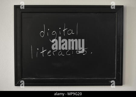 Alfabetizaciones digitales escritas en blanco tiza en una pizarra en la pared. Foto de stock